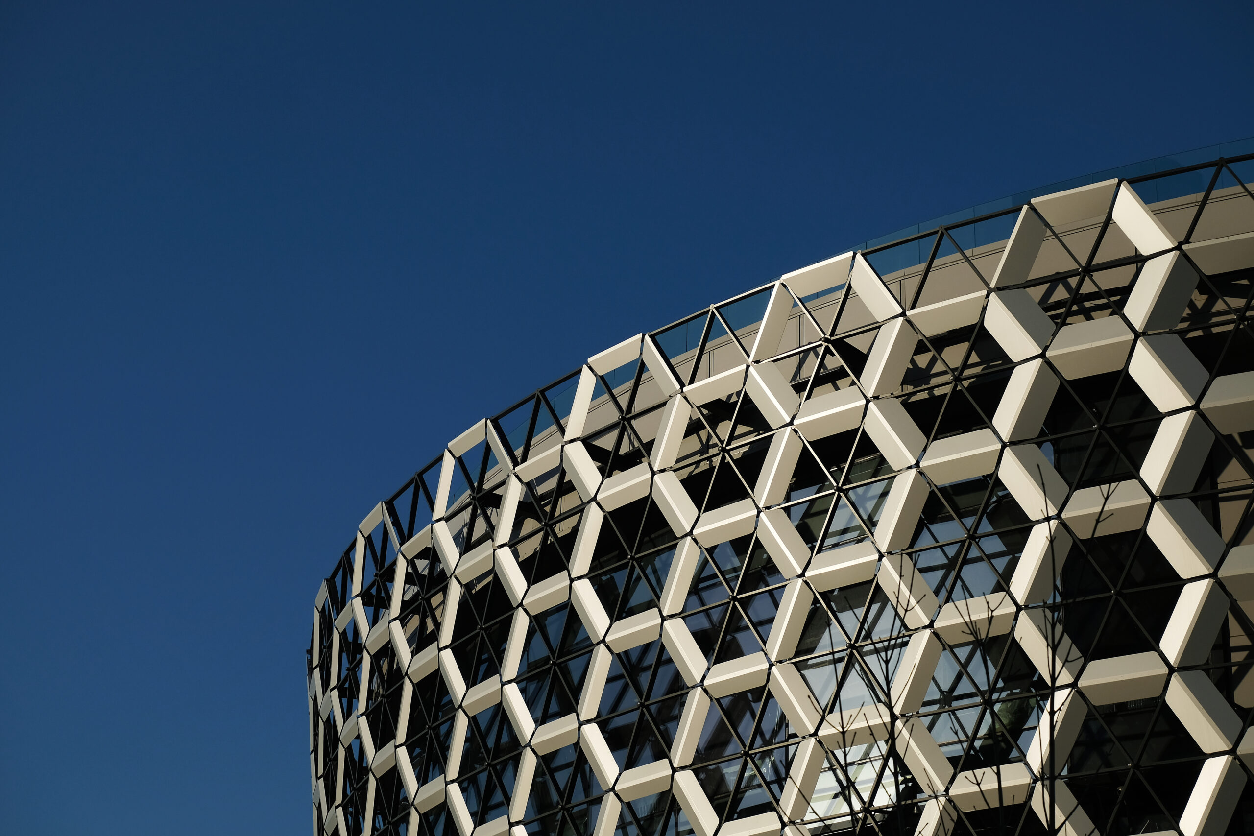 Kazan, Russia - 04 15 2021: Facade of a modern shopping center. A wall composed of honeycombs hexagons. Contemporary architecture, exterior. Blue sky